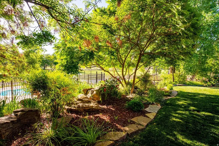 Lush backyard featuring a manicured lawn, established trees, and natural rock landscaping