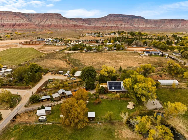 Expansive property featuring a residence with solar panels, a large greenhouse, and a manicured lawn