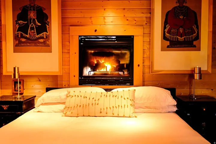 Fireplace with wood surround set into a wood-paneled wall, flanked by wall art