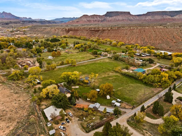 Expansive aerial perspective showcasing a rural landscape with scattered residences, green fields, and mature trees with yellow foliage