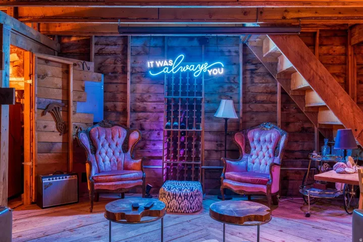 Rustic wood-paneled walls and exposed ceiling beams frame a unique lounge area
