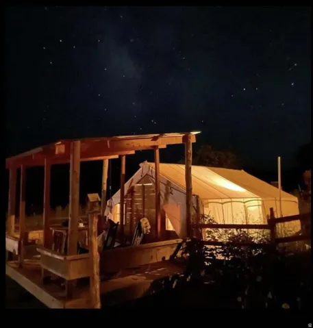 Outdoor living area featuring a wooden pergola and an illuminated canvas structure