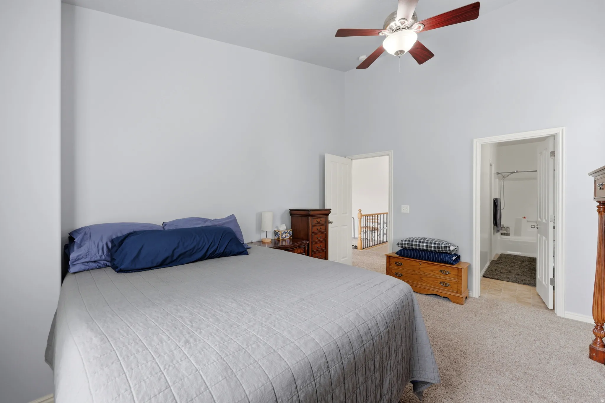 Carpeted bedroom with a vaulted ceiling and a ceiling fan with light fixture