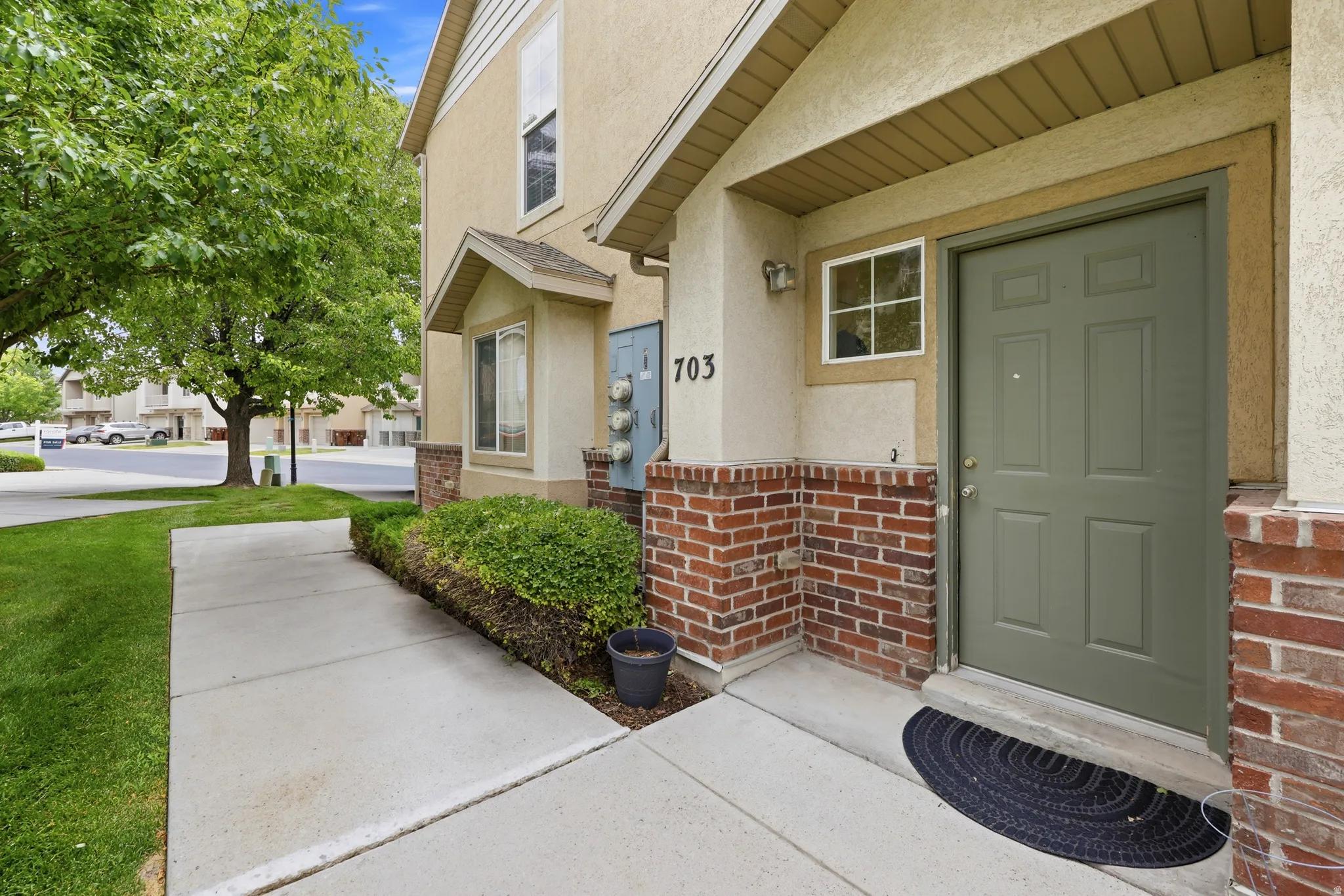 Stucco and brick facade featuring a panel-style entry door, bay window, and exterior lighting