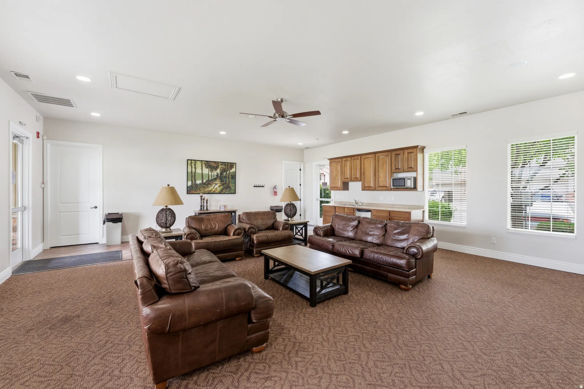 Spacious common area featuring textured carpeting, multiple recessed lights, and a ceiling fan