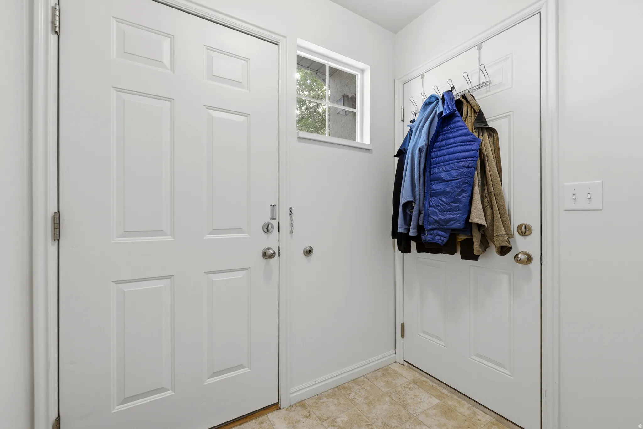 Entryway featuring two paneled doors, a transom window, light neutral wall paint, and tiled flooring