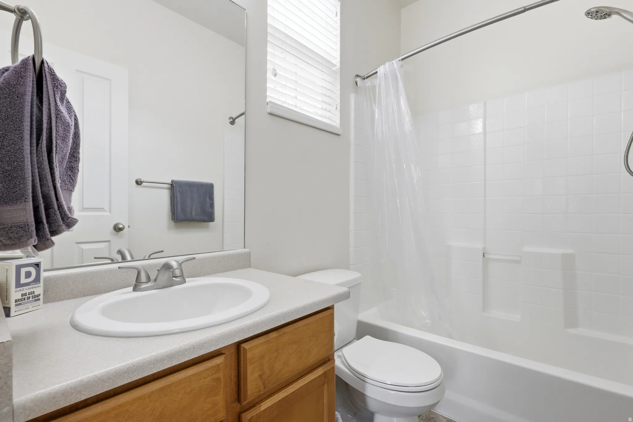 Bathroom featuring a light wood-finish vanity with a light countertop, an oval undermount sink, and a chrome faucet