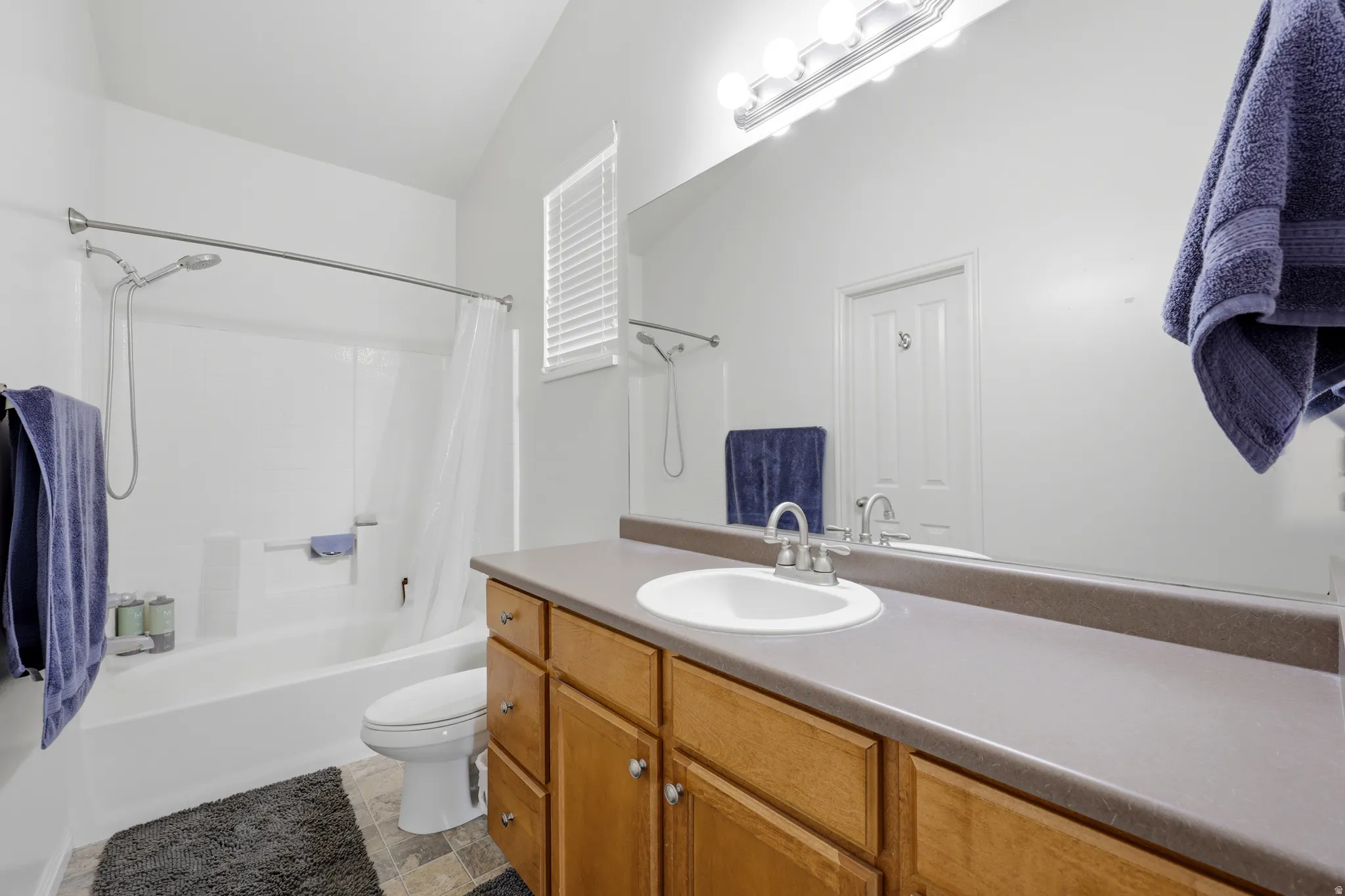Bathroom featuring a wood-finish vanity with a built-in sink and extensive countertop space