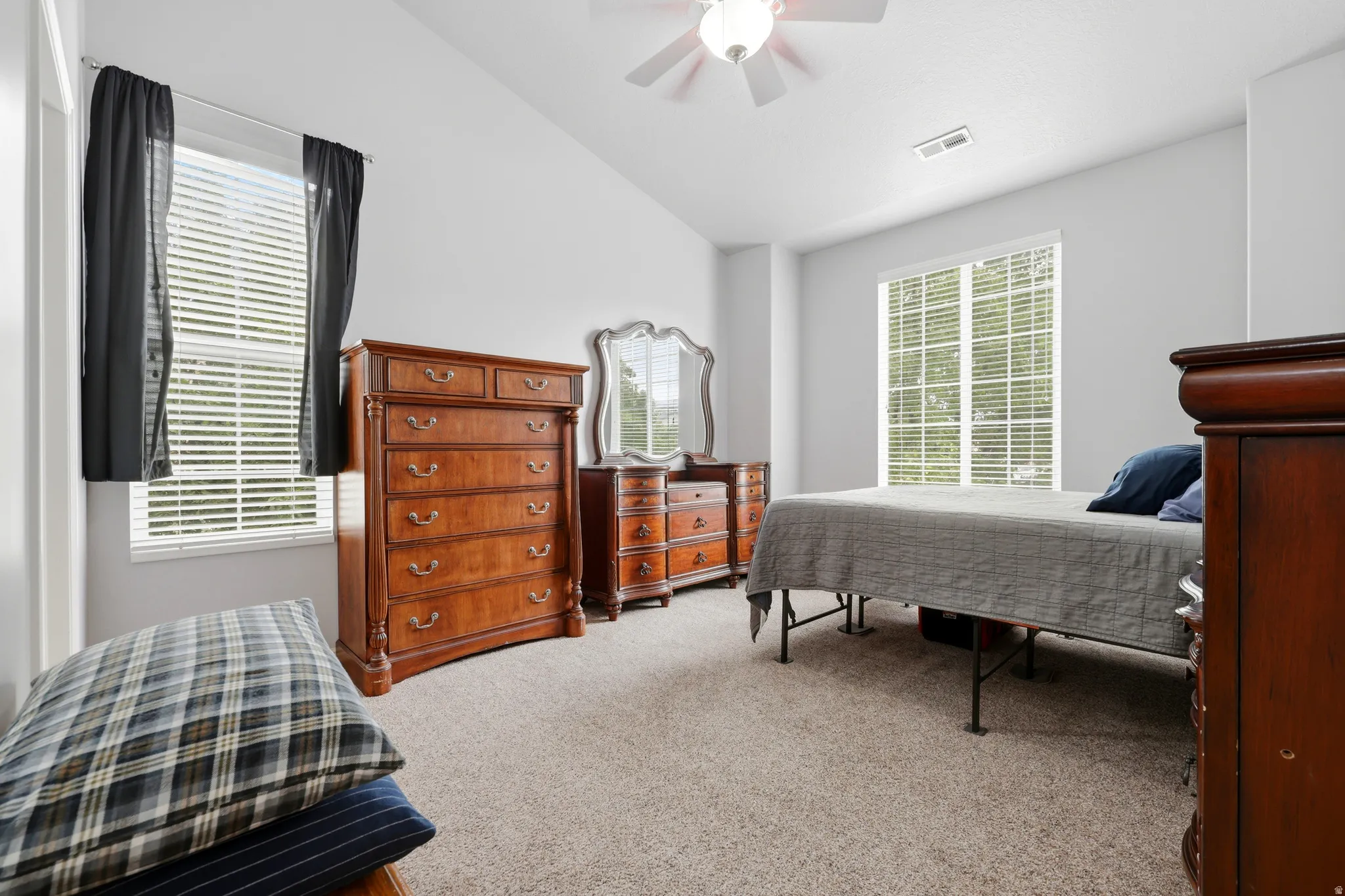 Spacious room featuring vaulted ceilings, a ceiling fan, and light-colored carpeting