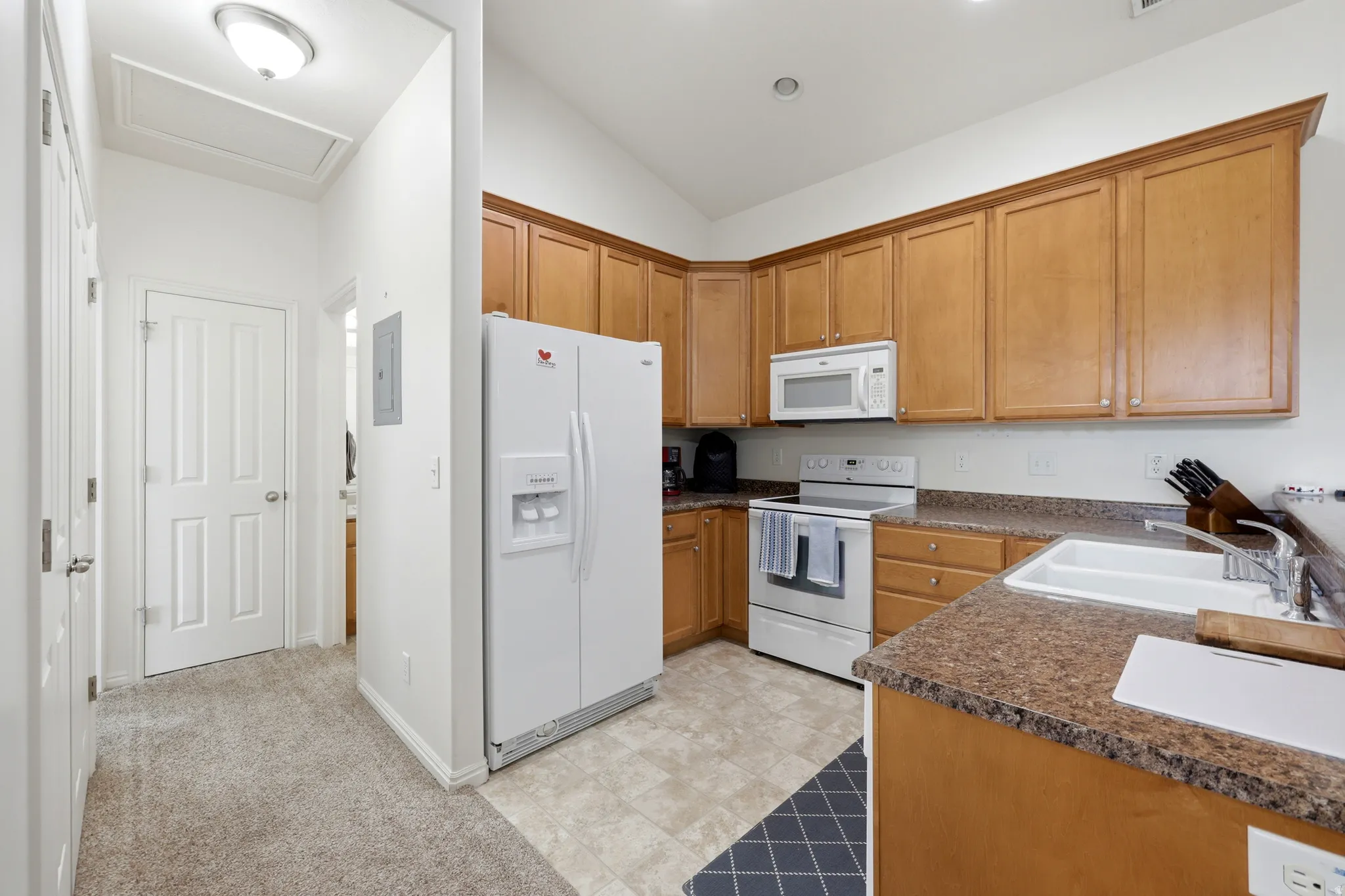 Kitchen featuring light wood cabinetry, white appliances, and a double basin sink
