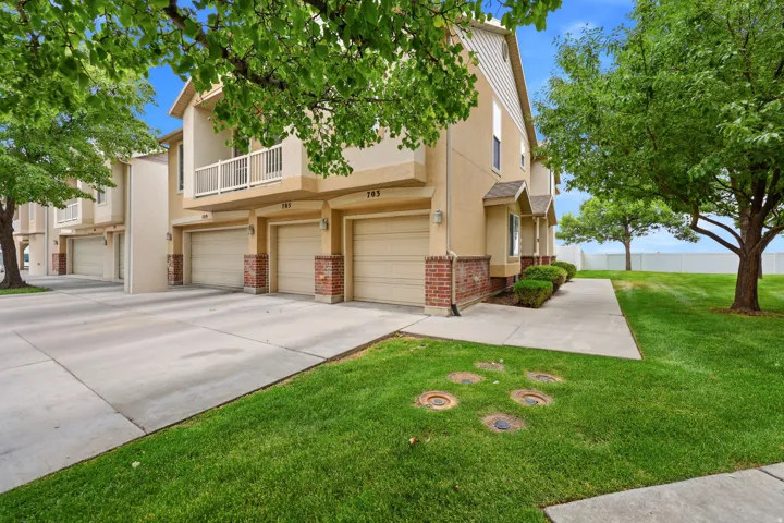 Multi-level townhome exterior featuring an attached garage, brick accents, and private balcony