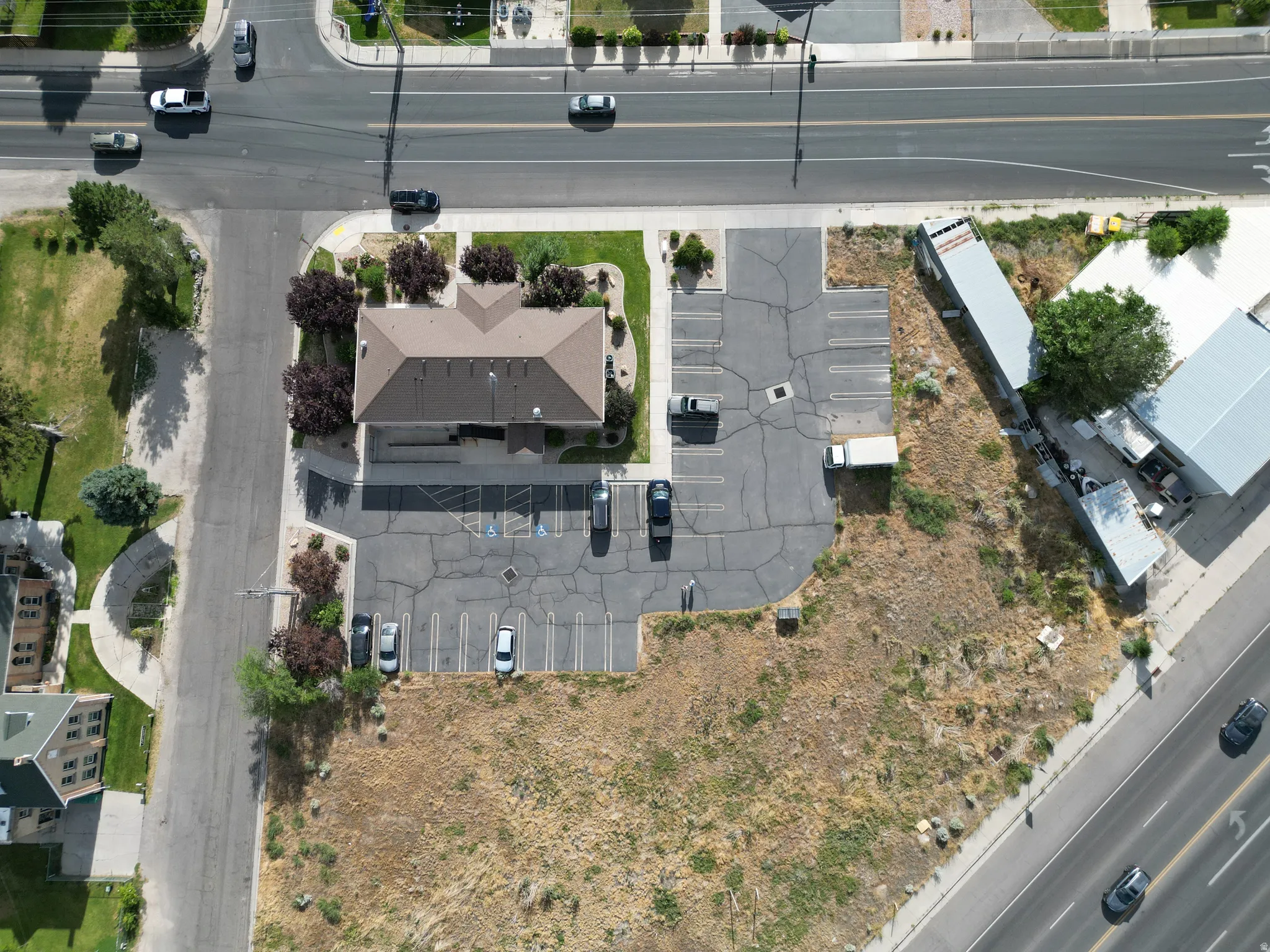 Commercial property featuring a multi-gable roofline, asphalt parking lot with marked spaces, and surrounding landscaping