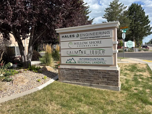 Business directory sign featuring a stone base, multiple business listings, and a white top cap