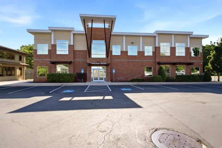 Two-story commercial building featuring brick and stucco facade, a prominent central entrance with double glass doors, and expansive windows