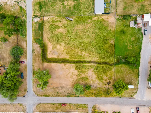 Expansive land parcel featuring a mix of green and dry vegetation, bordered by unpaved roads and visible property lines