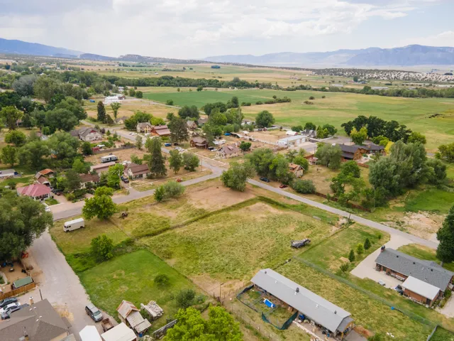 Rural landscape featuring diverse residential properties and extensive open fields, bordered by distant mountains