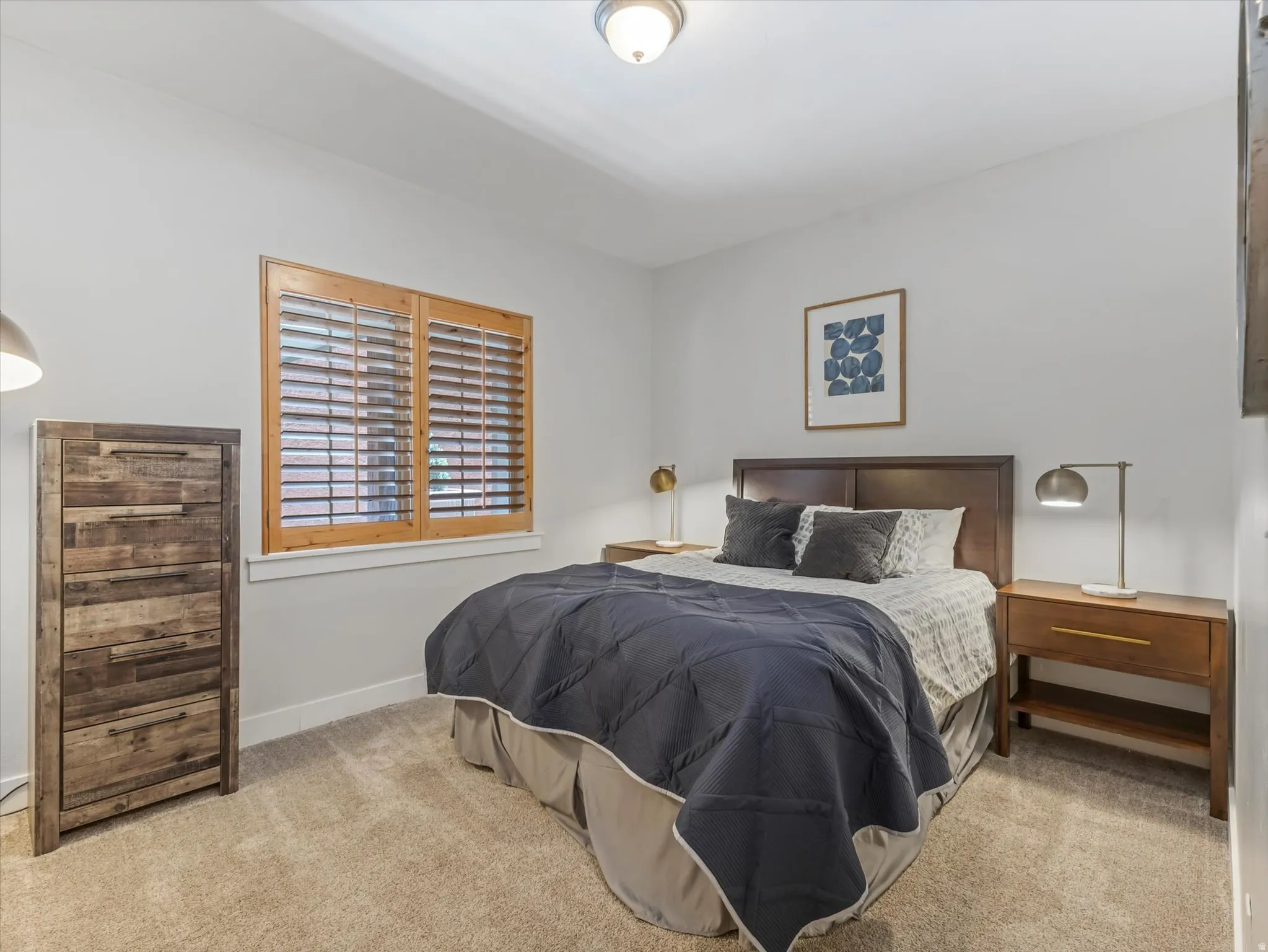 Carpeted room featuring a window with wood plantation shutters, a dark wood headboard, and recessed lighting