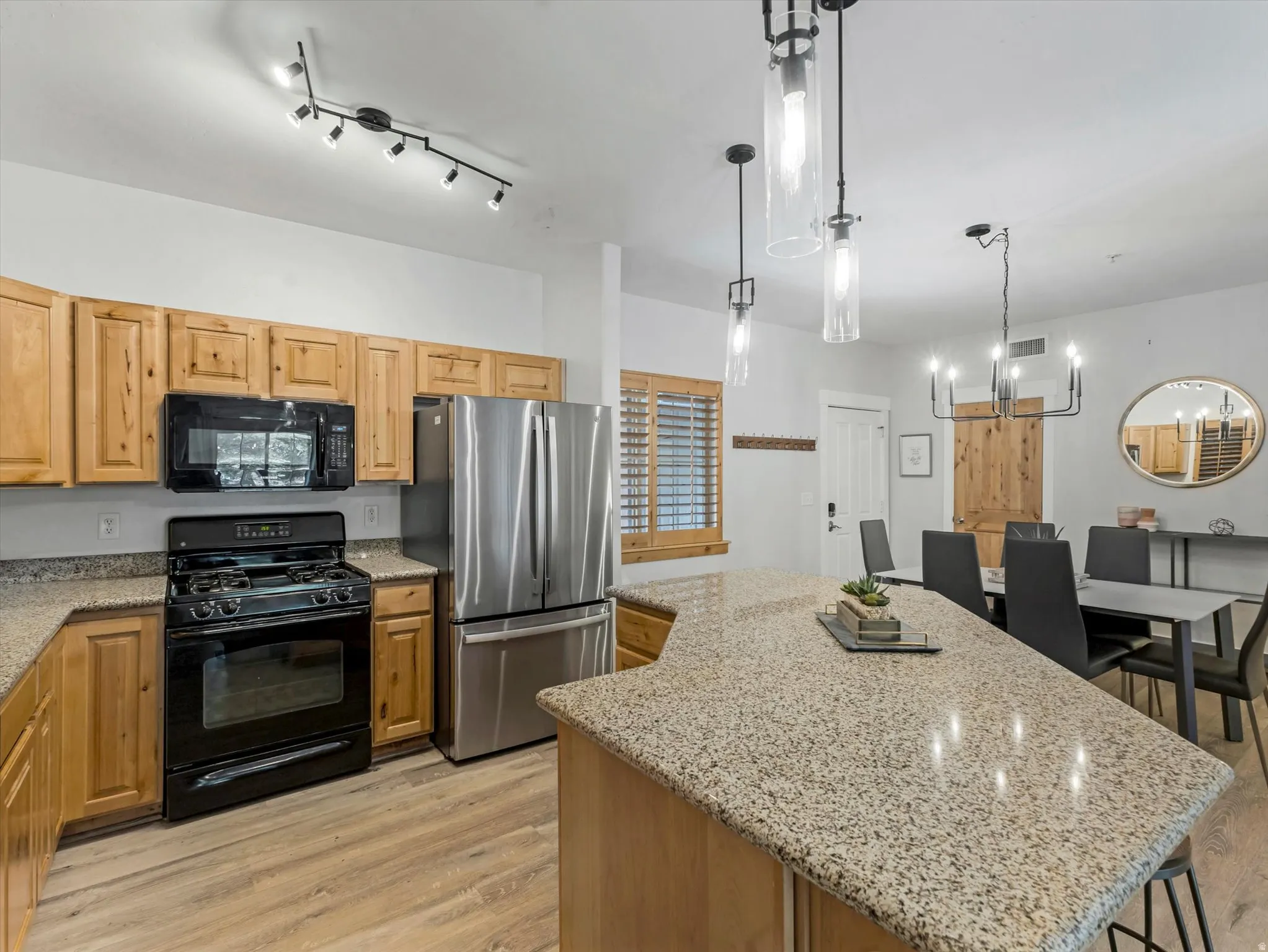 Kitchen featuring natural wood cabinetry, granite countertops, and wood-finish flooring