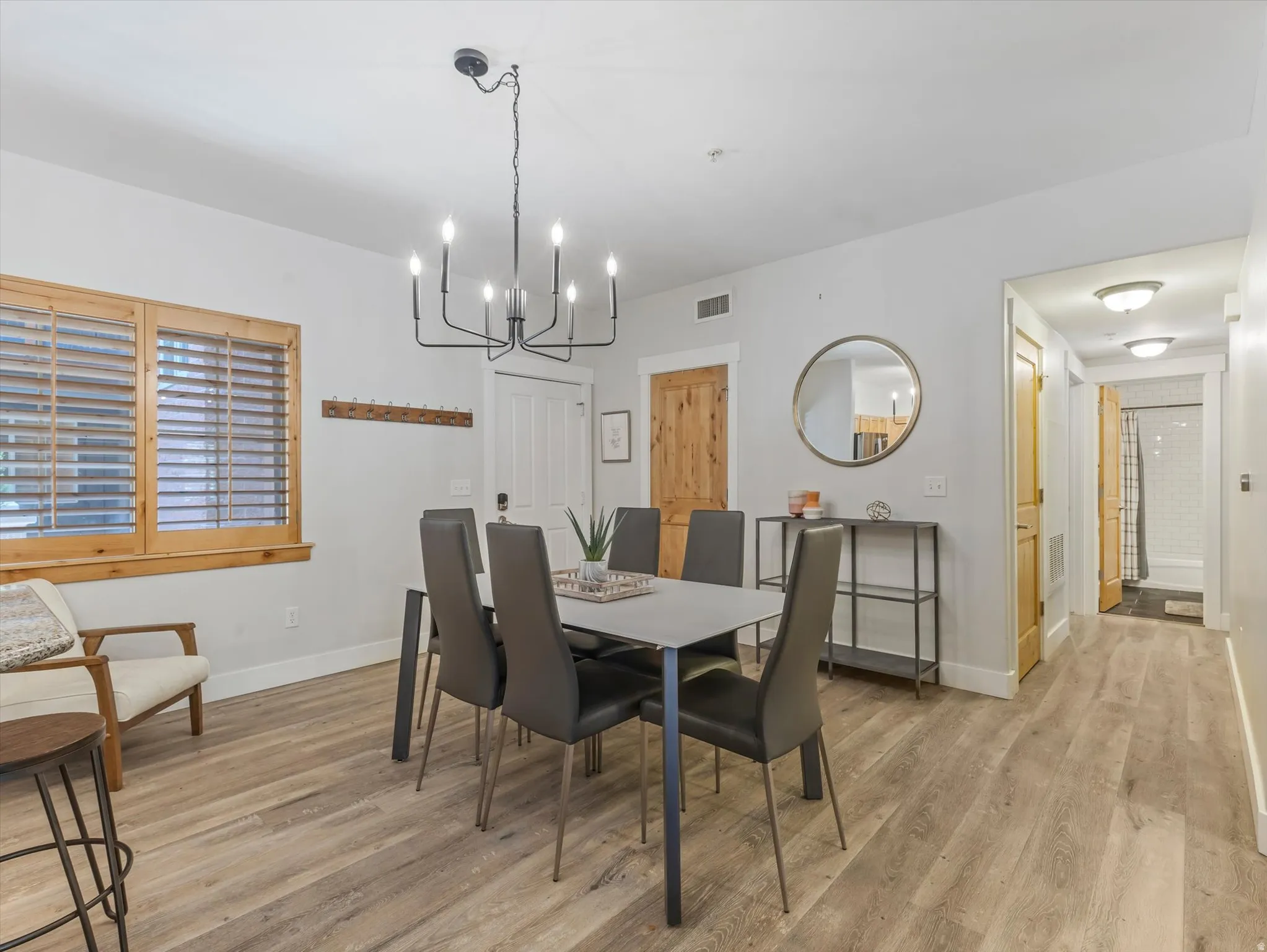 Open-concept dining area featuring wood-finish flooring, a contemporary black chandelier, and light-toned walls
