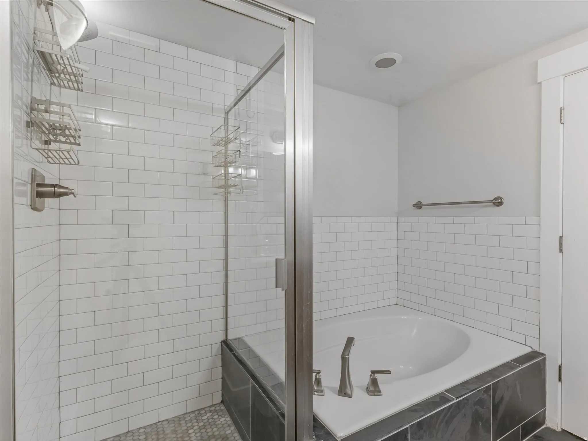 Bathroom featuring a subway tile shower enclosure with a glass door, a dark tile shower pan, and a built-in corner soaking tub with dark tile surround