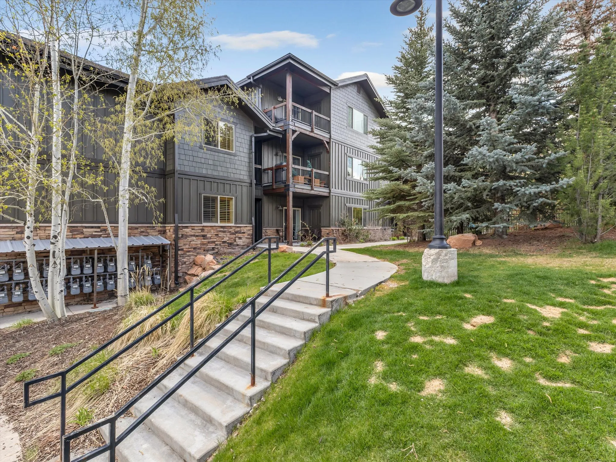 Multi-story building featuring dark siding, stone veneer accents, and multiple private balconies