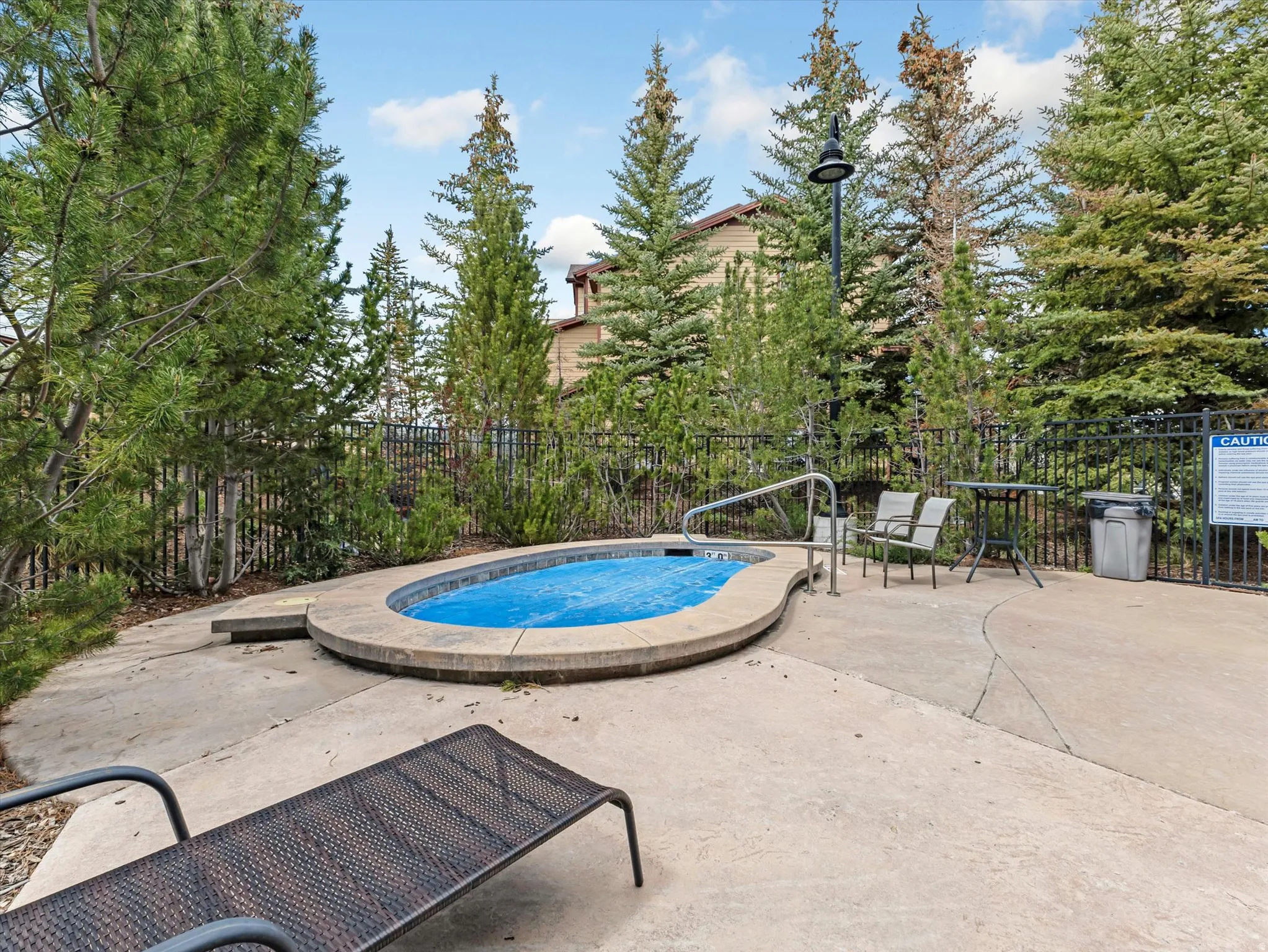Outdoor spa featuring a curved perimeter, concrete surround, and metal railing