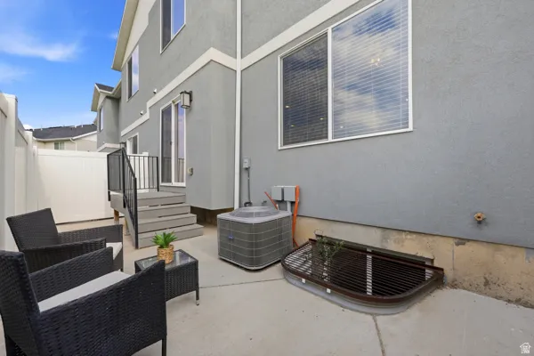 Outdoor patio area featuring a concrete surface, gray exterior siding, and a white privacy fence