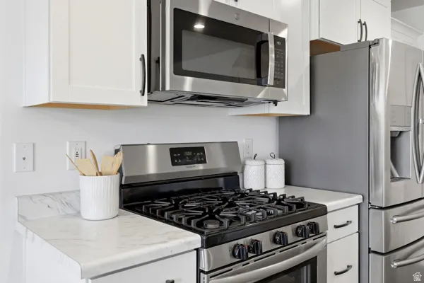 Kitchen featuring stainless steel appliances, white cabinetry with dark hardware, a gas range, an over-the-range microwave, and white countertops