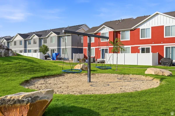 Community green space featuring a sand play area with swings, surrounded by a manicured lawn