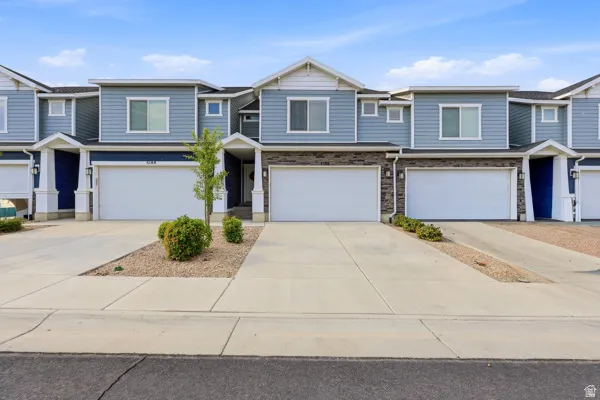 Townhome exterior featuring light blue horizontal siding, dark blue accent panels, white trim, and a stone facade