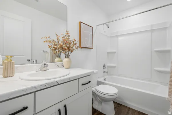 Bathroom featuring a vanity with a white marbled countertop, integrated sink, and white cabinetry with matte black pulls