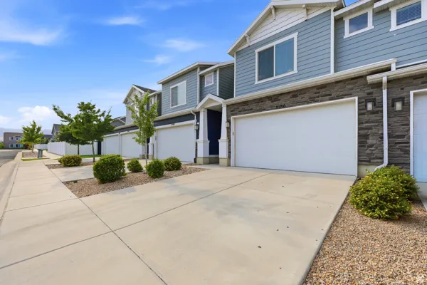 Townhome exterior featuring blue siding, stone facade accents, white garage door, and a concrete driveway