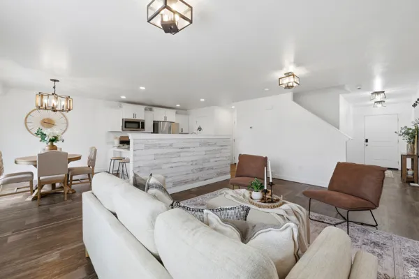 Open-concept living area featuring wood-finish flooring, white walls, and contemporary light fixtures