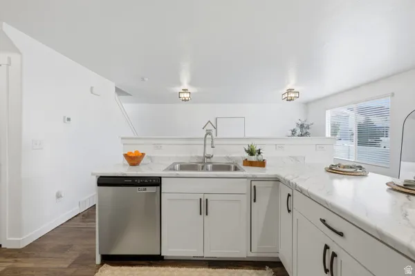 Kitchen featuring a stainless steel double sink, white cabinetry with black hardware, and light-colored countertops