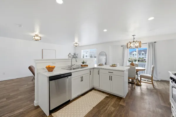 Open-concept kitchen featuring white cabinetry, stainless steel appliances, a stainless steel sink, and wood-finish flooring