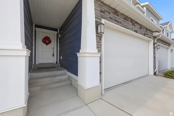 Inviting front entry featuring a white door, concrete steps, and dark blue siding