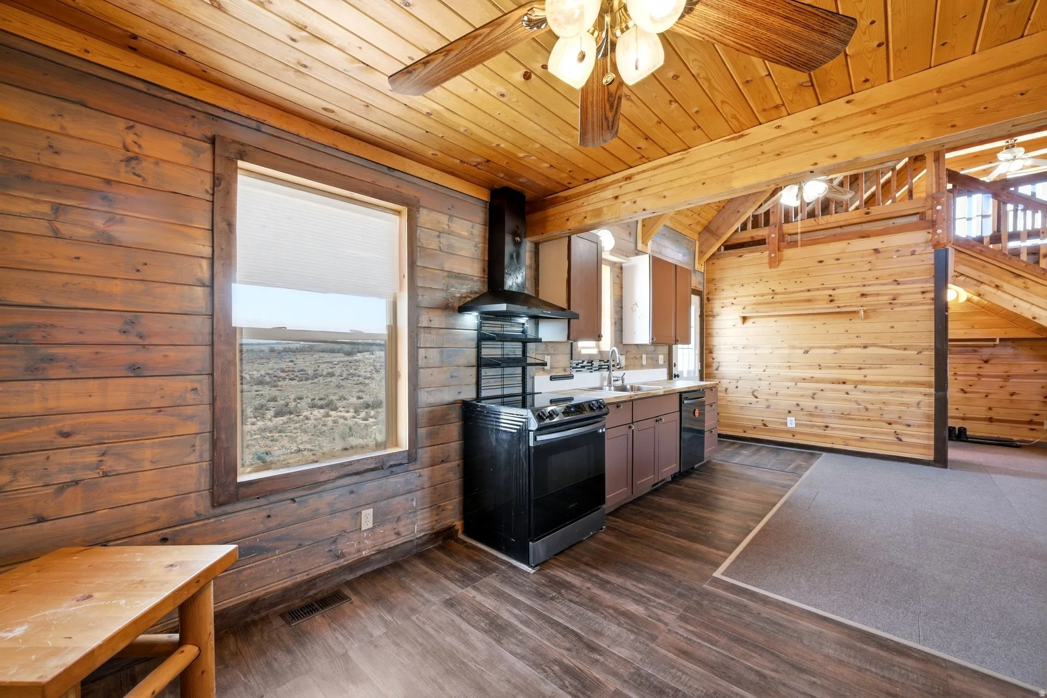 Open-concept living space with extensive wood paneling, wood-finish flooring, and a vaulted wood-beam ceiling