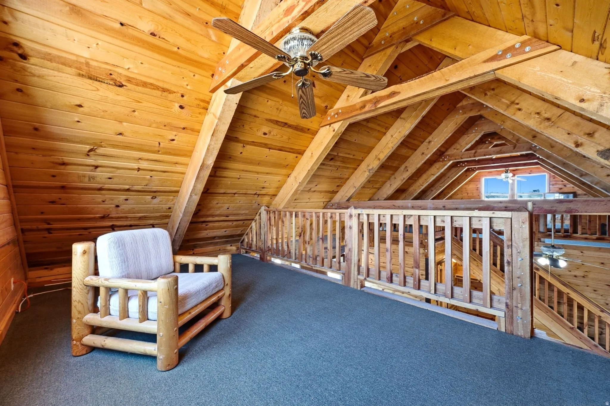 Loft space featuring exposed wood beams and a slatted wood railing
