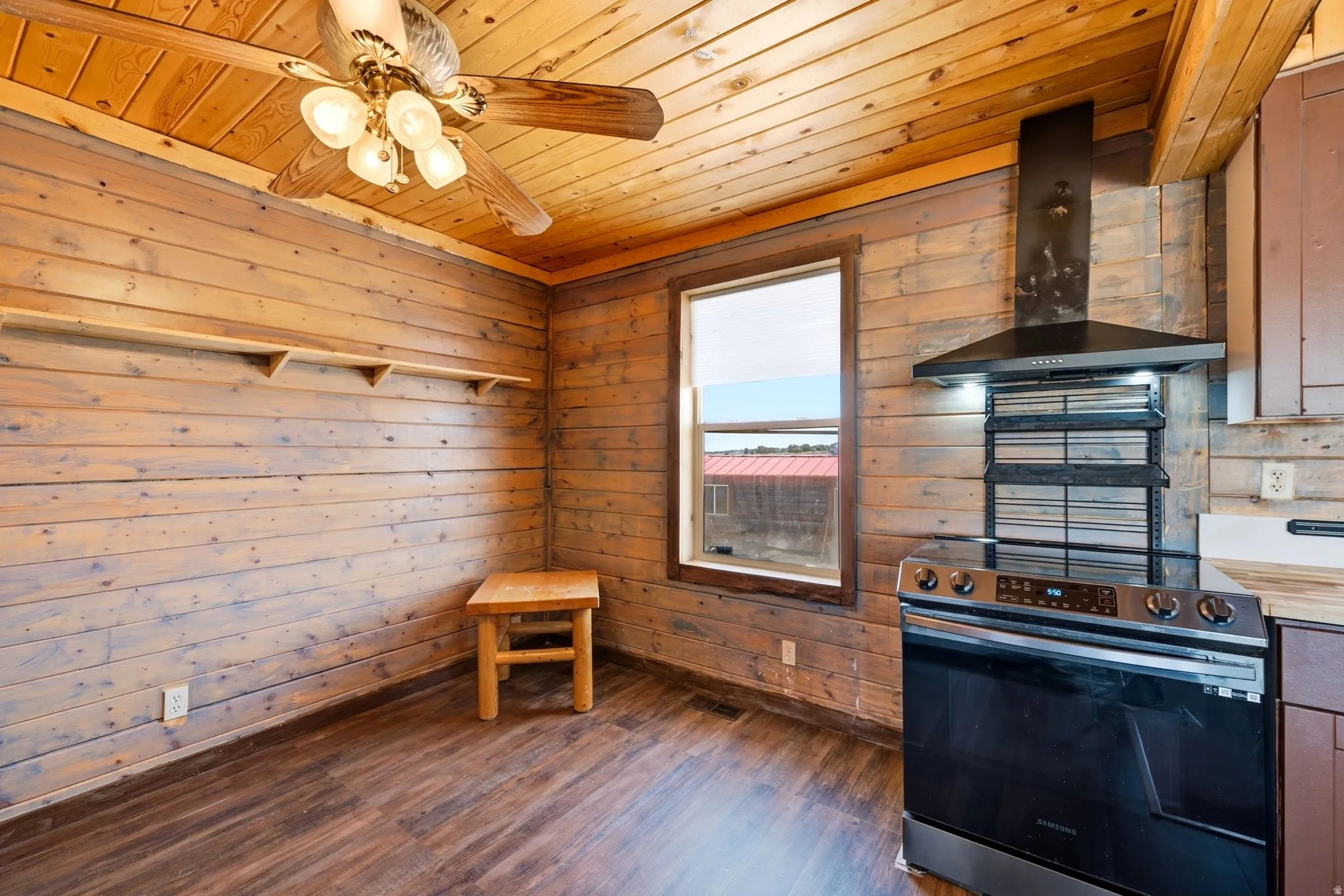 Room featuring wood-finish flooring, wood plank walls, and a wood plank ceiling with a ceiling fan