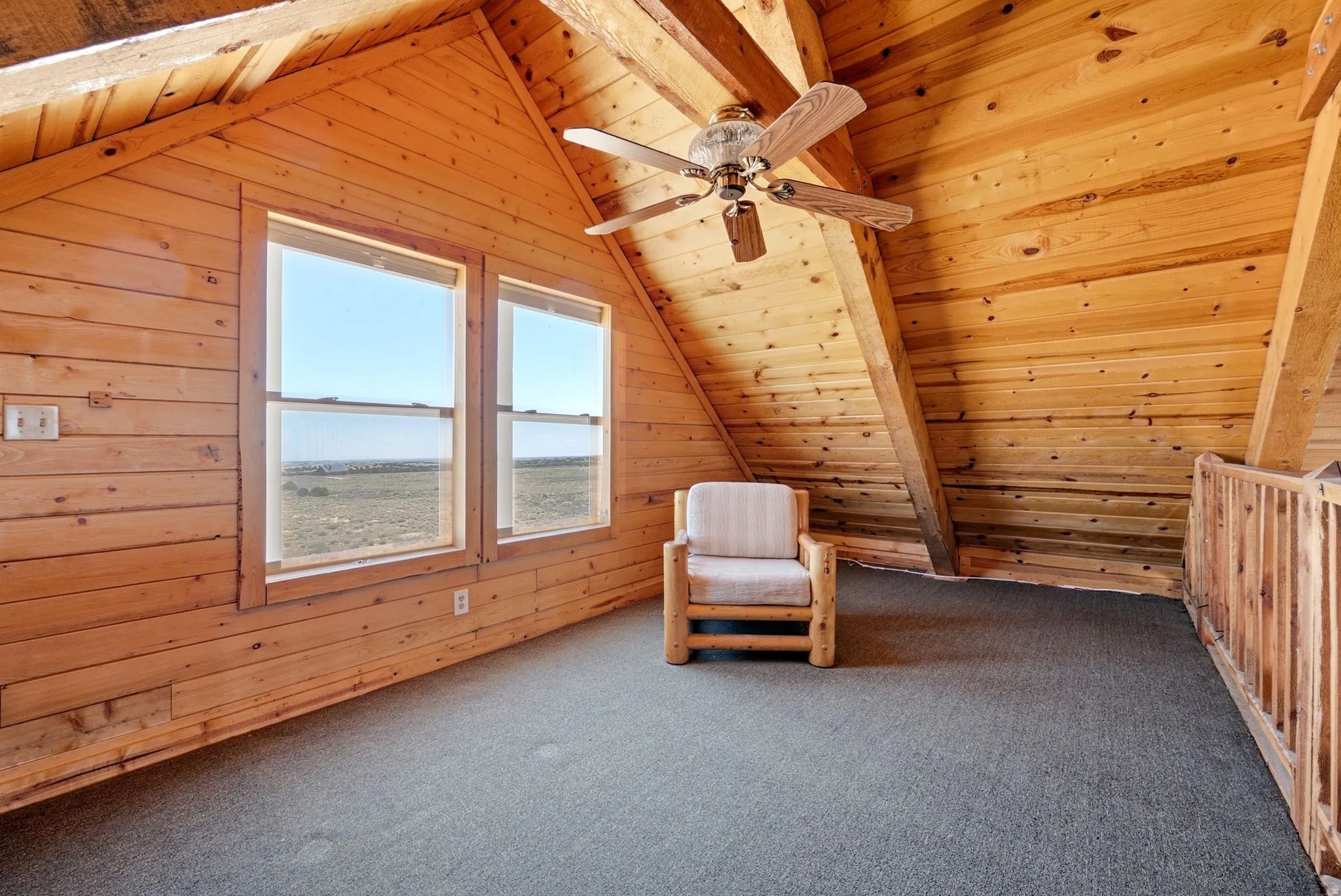 Wood-paneled room with vaulted ceilings, exposed beams, and two double-hung windows