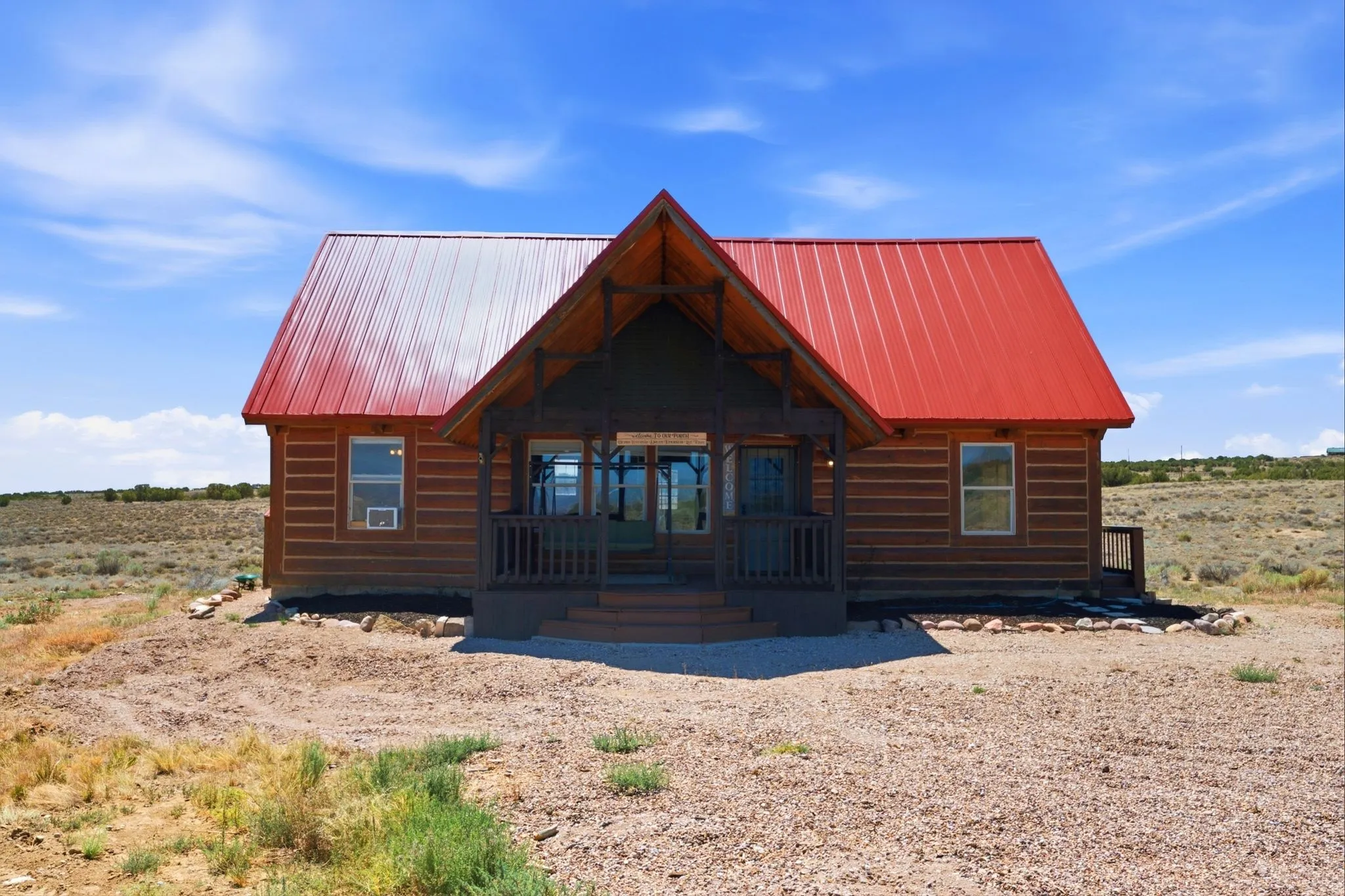 Log cabin style exterior featuring a vibrant red metal roof