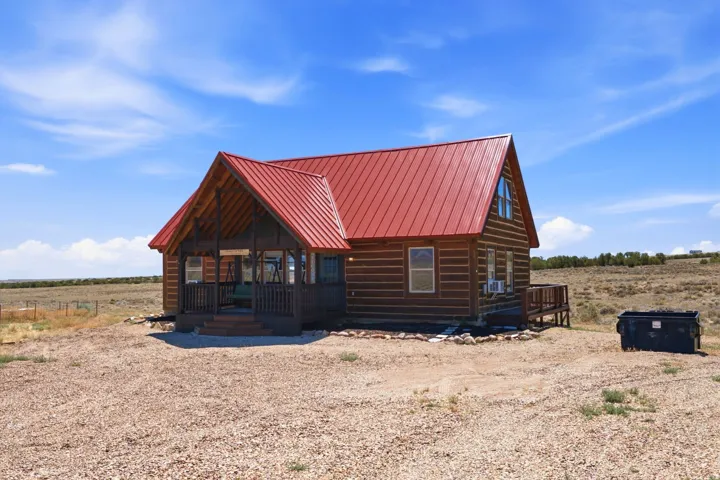 Log cabin residence featuring a vibrant red metal roof and natural wood siding
