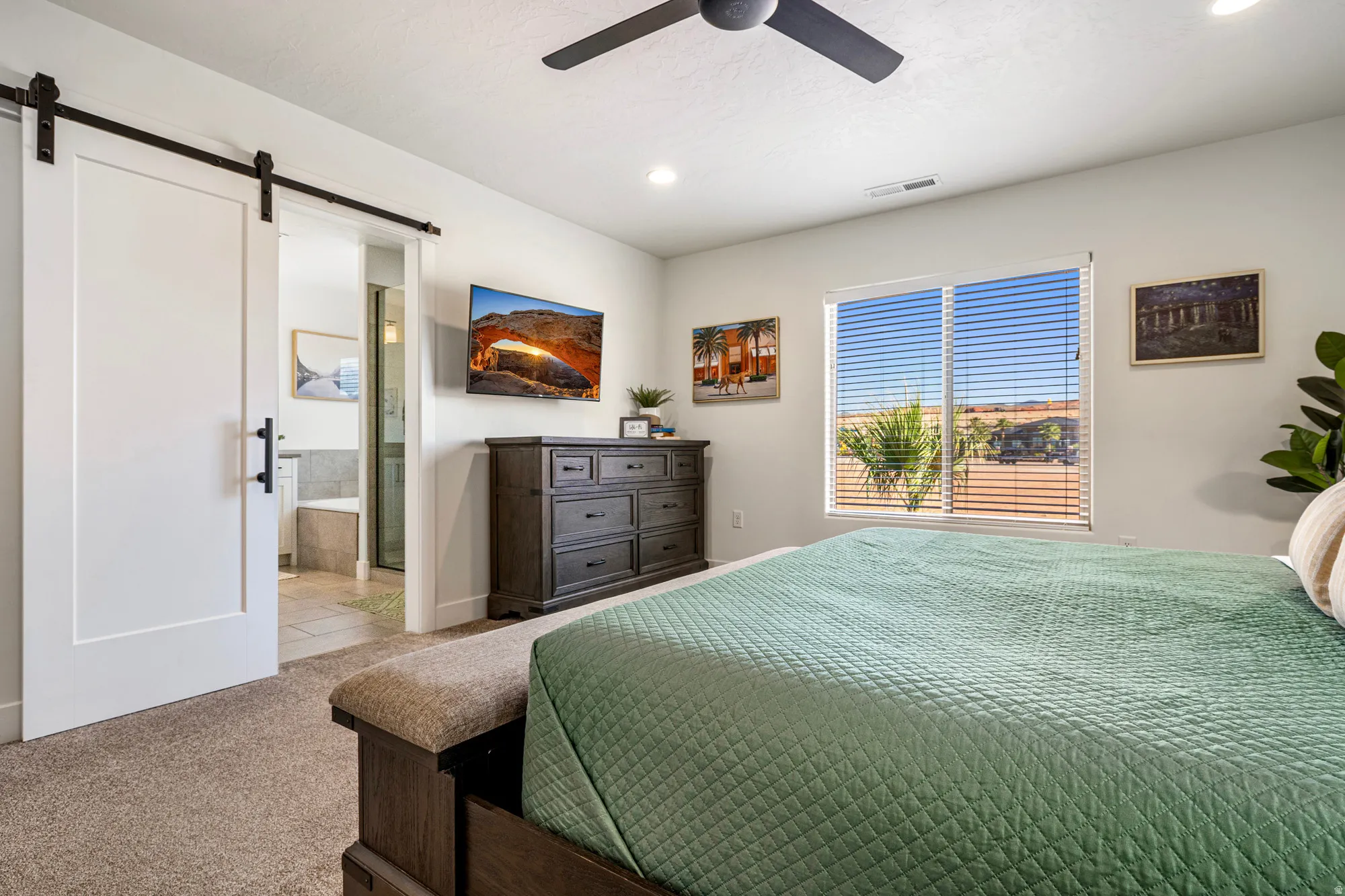 Bedroom featuring a modern ceiling fan, recessed lighting, and a barn door entry to a bathroom with a built-in tub