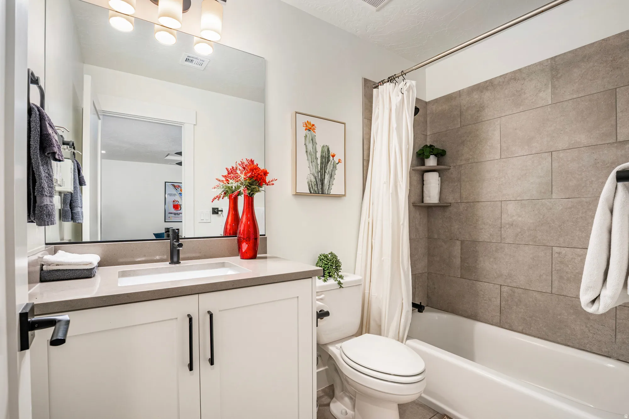 Bathroom featuring a white vanity with a light-toned countertop, an undermount sink with a matte black faucet, and a large mirror