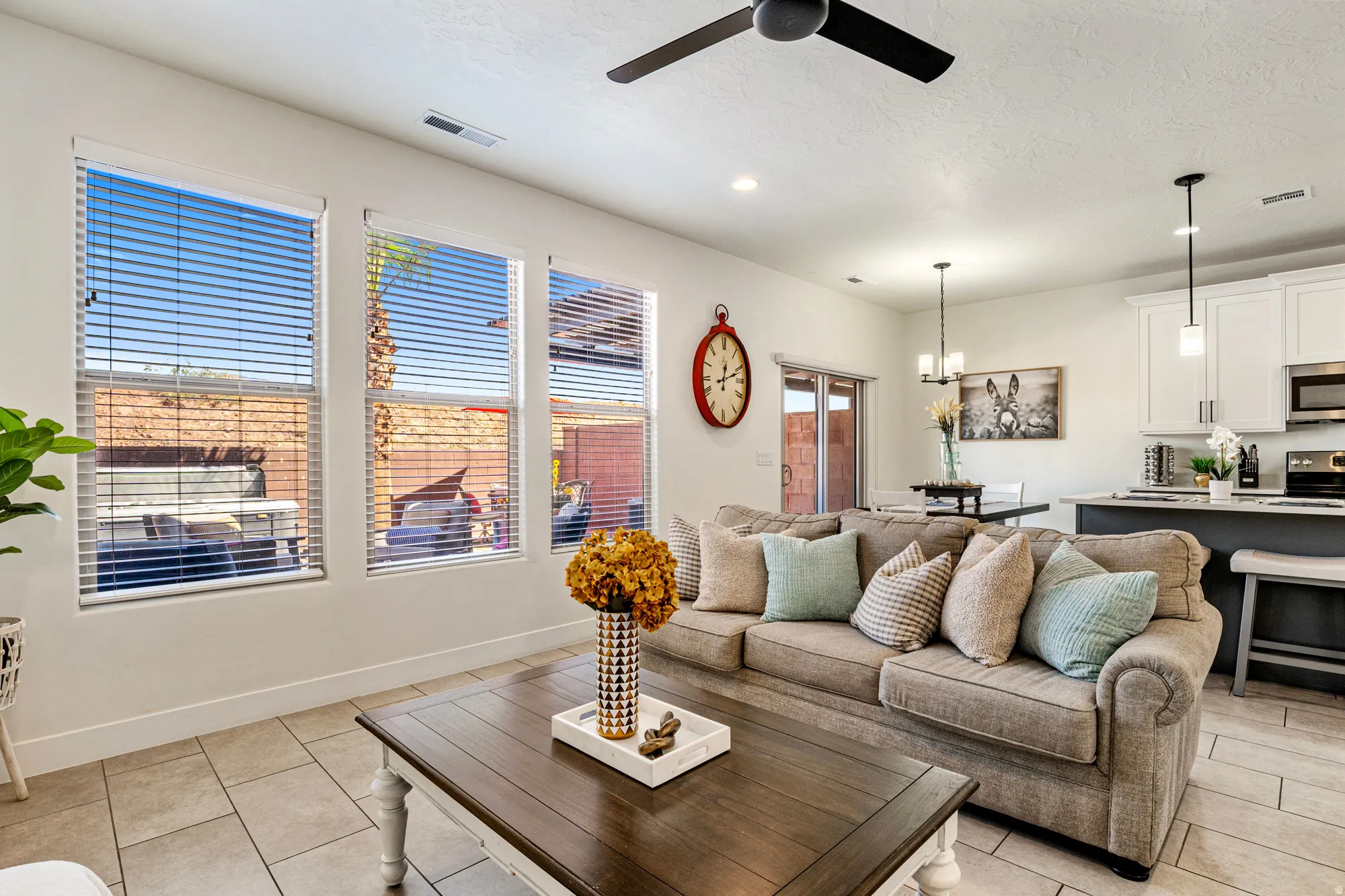 Open-concept living area featuring multiple windows with horizontal blinds, recessed lighting, and a ceiling fan