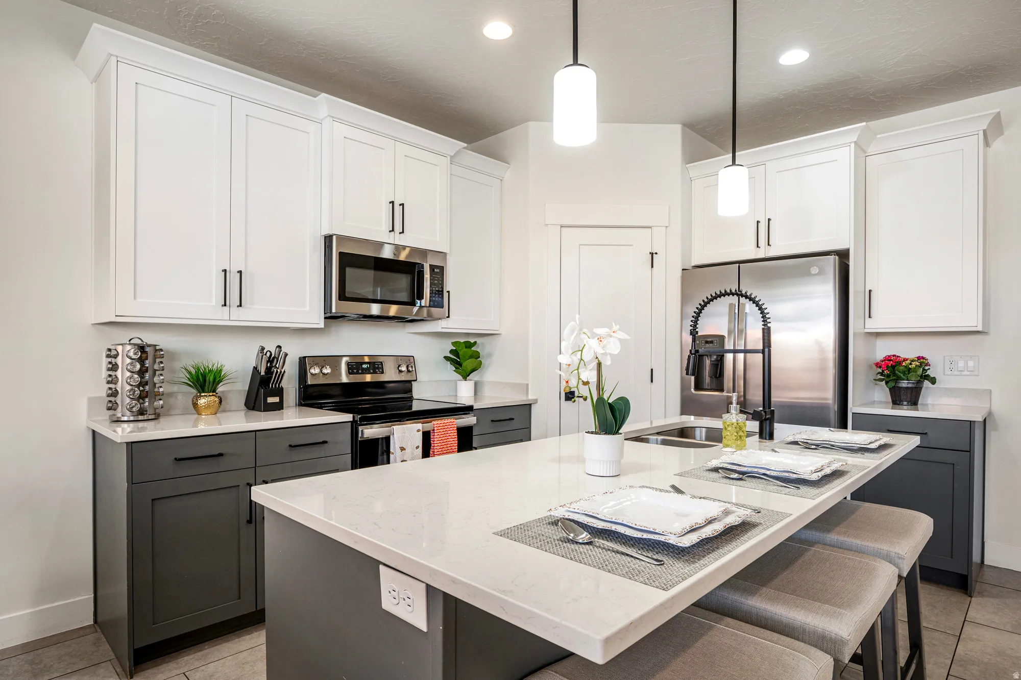 Contemporary kitchen featuring a large island with seating, stainless steel appliances, two-tone cabinetry, recessed lighting, and pendant fixtures