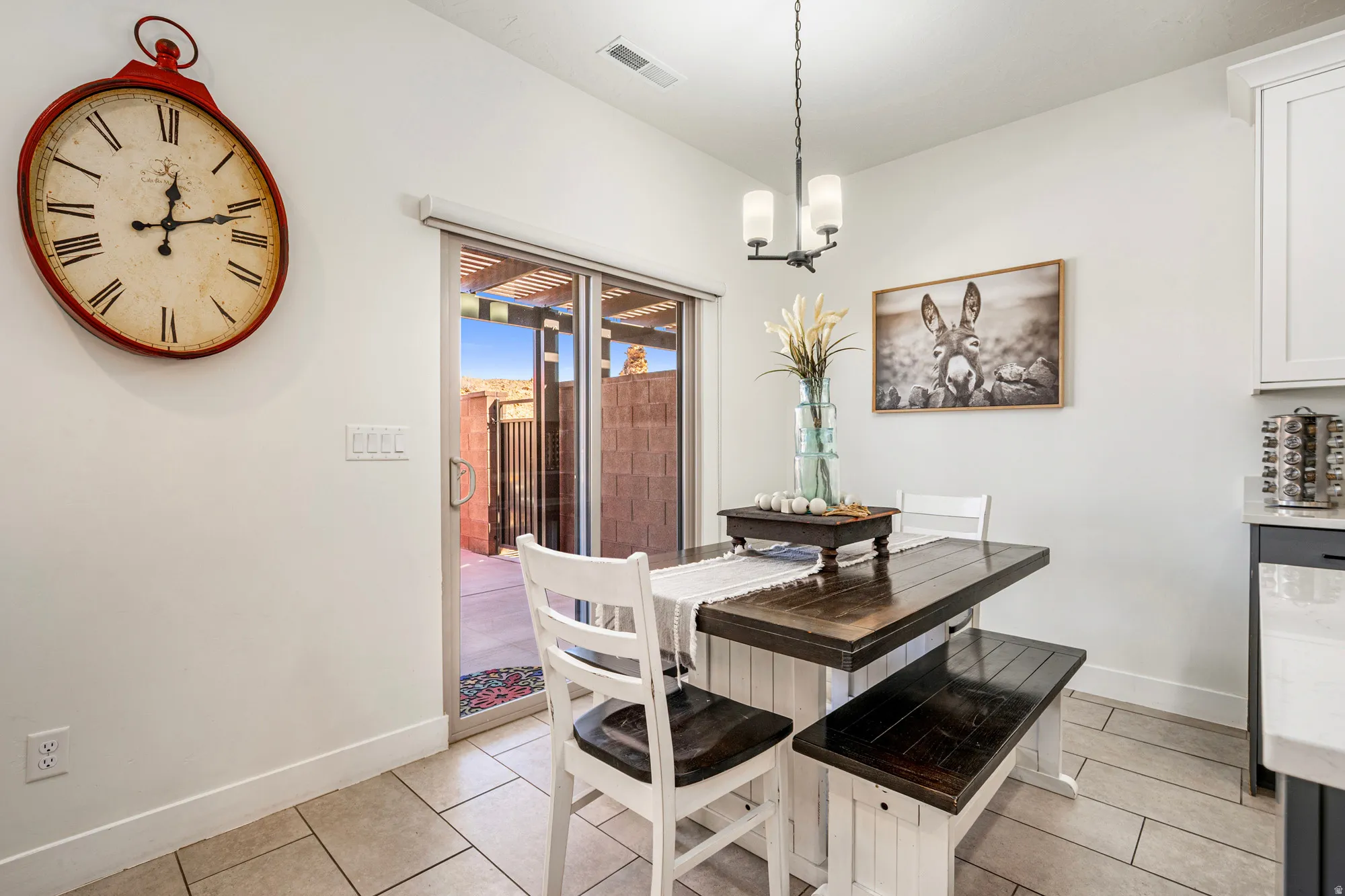Dining area with a dark wood-finish table, white bench seating, and ceramic tile flooring