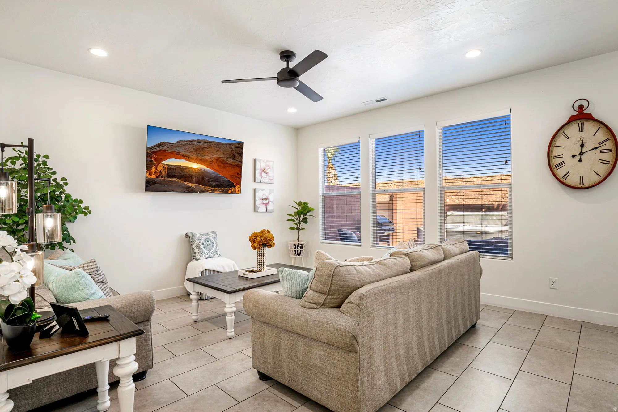 Bright living space featuring recessed lighting, a ceiling fan, and three windows with horizontal blinds