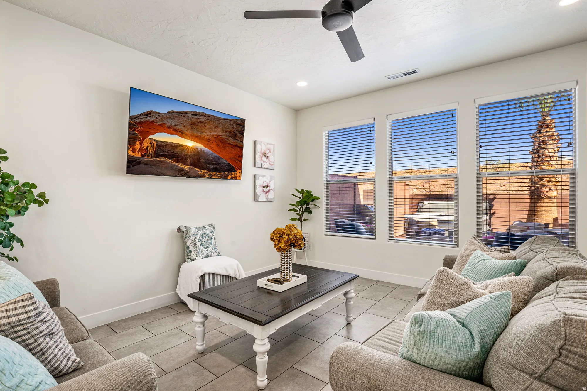 Living area featuring tile flooring, three large windows with horizontal blinds, recessed lighting, and a ceiling fan