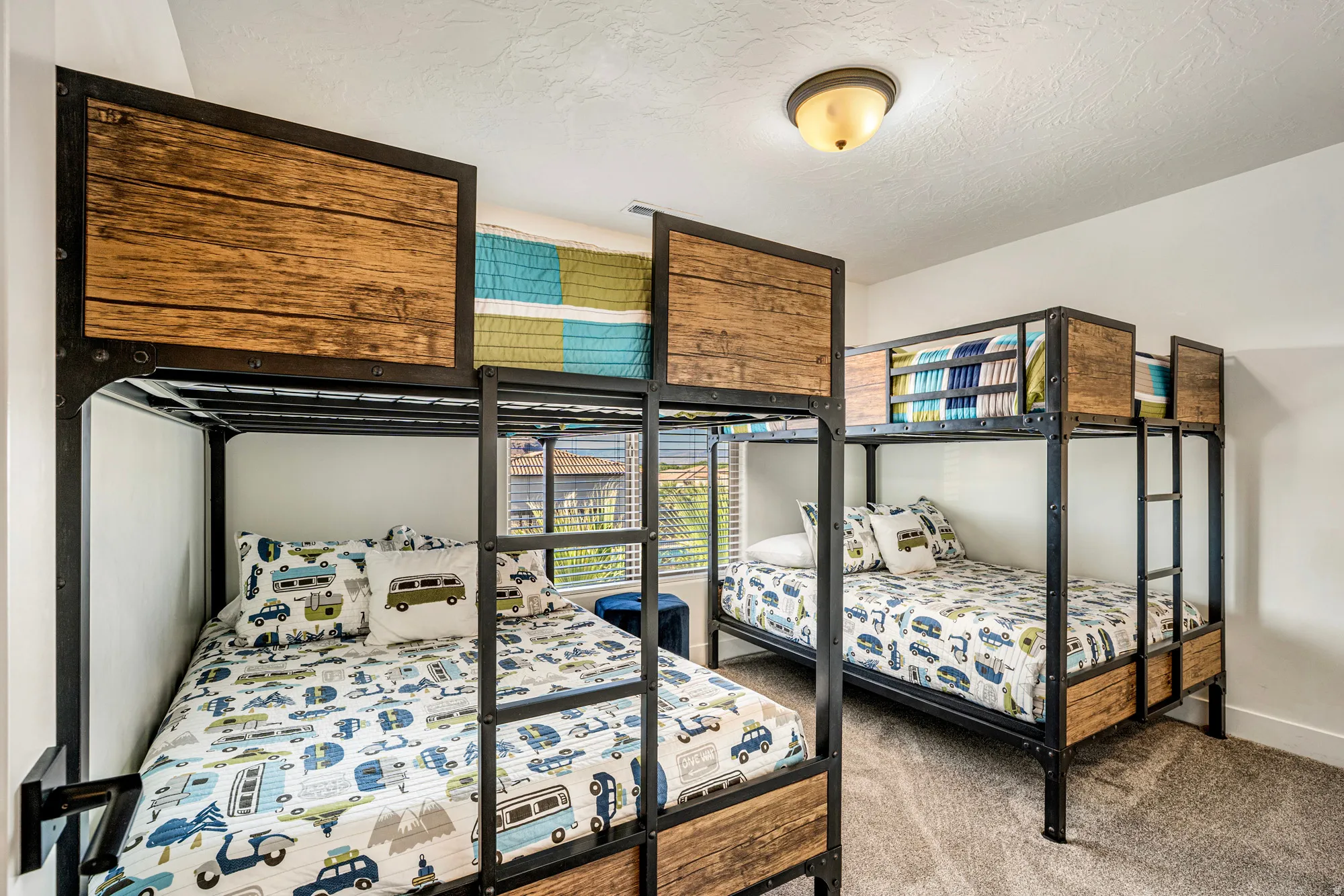 Bedroom featuring two sets of industrial-style bunk beds with wood-finish panels, neutral carpeting, and a window with horizontal blinds